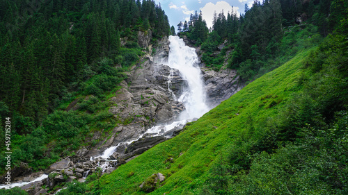 Krimml waterfalls with a green meadow in the foreground and a spruce forest. Mountain landscape. Nordic landscape. Whitewater in the Alps. Landscape photography