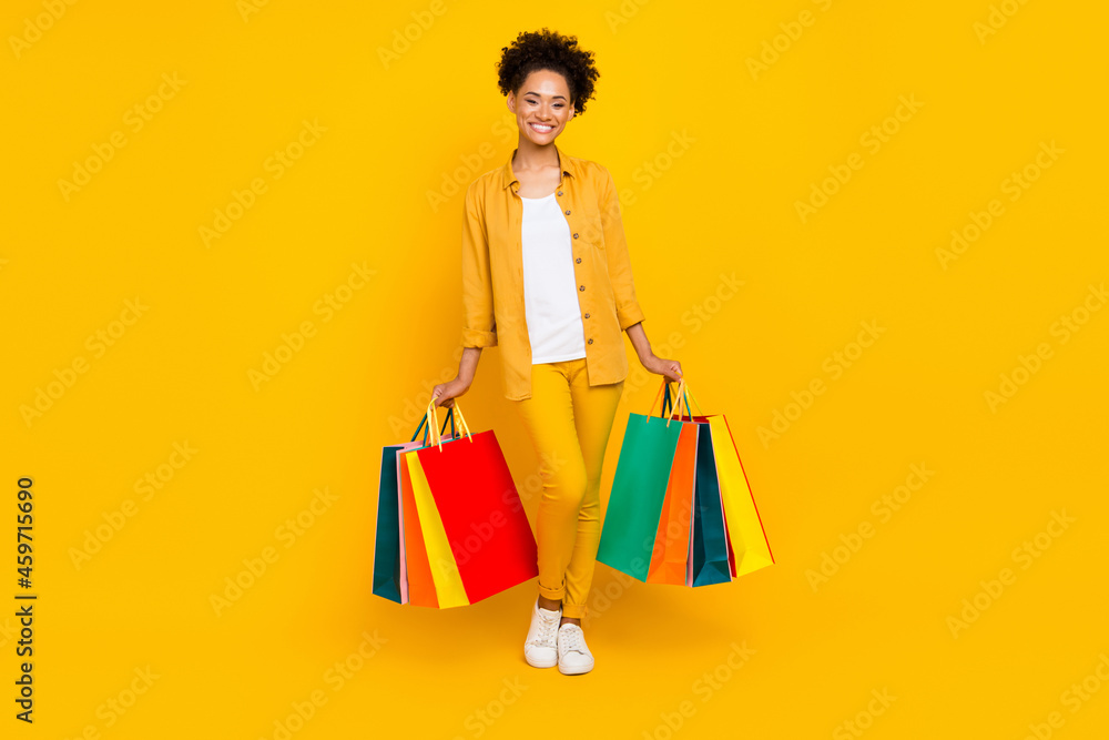 Full length body size photo woman keeping bags on shopping isolated vivid yellow color background Full length body size photo woman keeping bags on shopping isolated vivid yellow color background