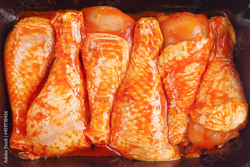 Raw chicken drumstick with spices and green rosemary on a black background .Convenience food, precooked.Cooking chicken drumsticks.Top view.Marinated chicken dramstick on a grill pan with spices . photo