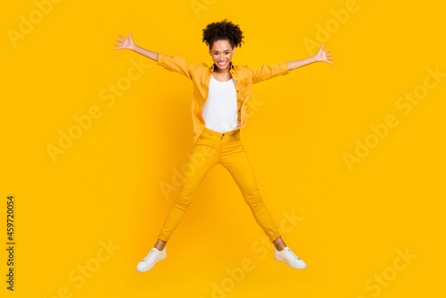 Full length body size photo woman jumping up playful happy isolated vivid yellow color background