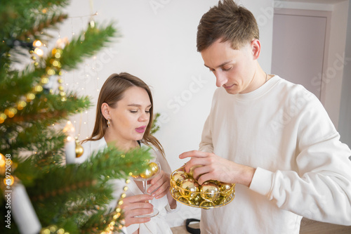 Happy couple decorating Christmas tree together at home