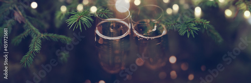 Champagne glasses on christmas background with golden bokeh lights and short depth of field. Greetings for merry christmas and holidays