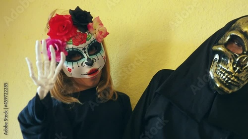 Children dressed in black costumes and scary Halloween masks. Girl in a Mexican Kalaka Calavera mask. A boy wearing a horrible skull mask with a black hood. All Hallows Eve or All Saints Eve theme photo