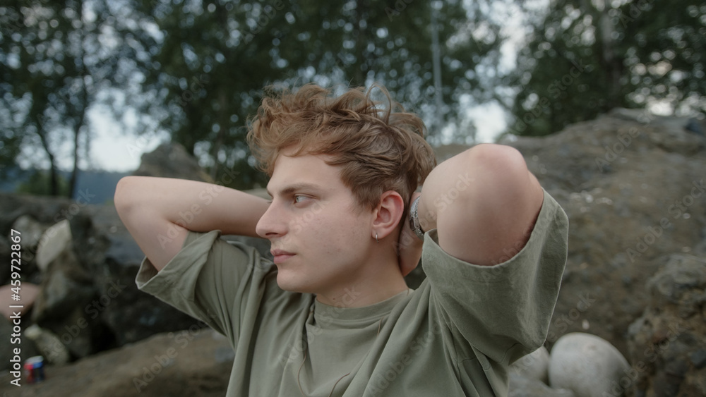 Young blond boy sitting in open space irritable and stressed drives away and gets lost in thought Young blond boy sitting in open space irritable and stressed drives away and gets lost in thought