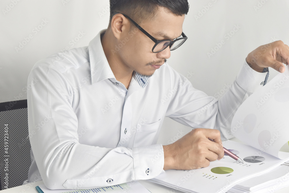 Handsome asian businessman working from home. Man analyzing financial graph and chart report.