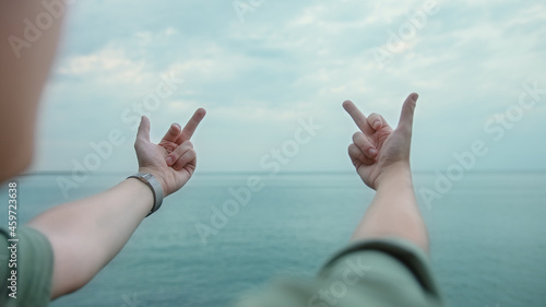 Young blonde man showing middle fingers gesture with both hands towards the sea
