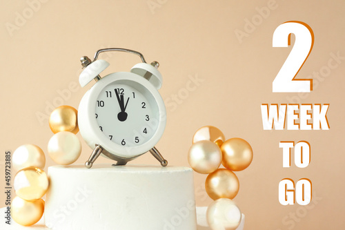 white alarm clock on a stand, 3D balls and the inscription 2 weeks to go..