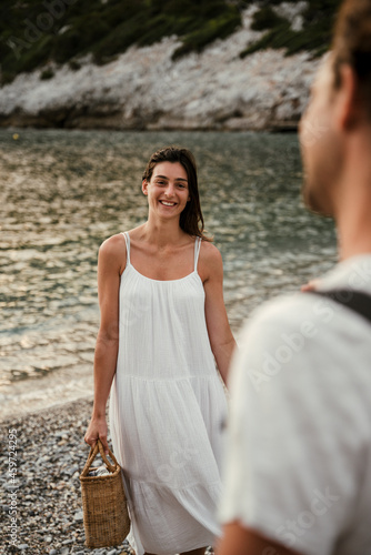 Caucasian female walking on beach smiling while walking towards boyfriend