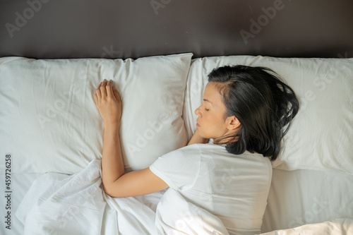 ..Peaceful serene beautiful young lady wear pajamas lying asleep relaxing sleeping in cozy white bed on soft pillow resting covered with blanket enjoying good healthy sleep concept, above top view