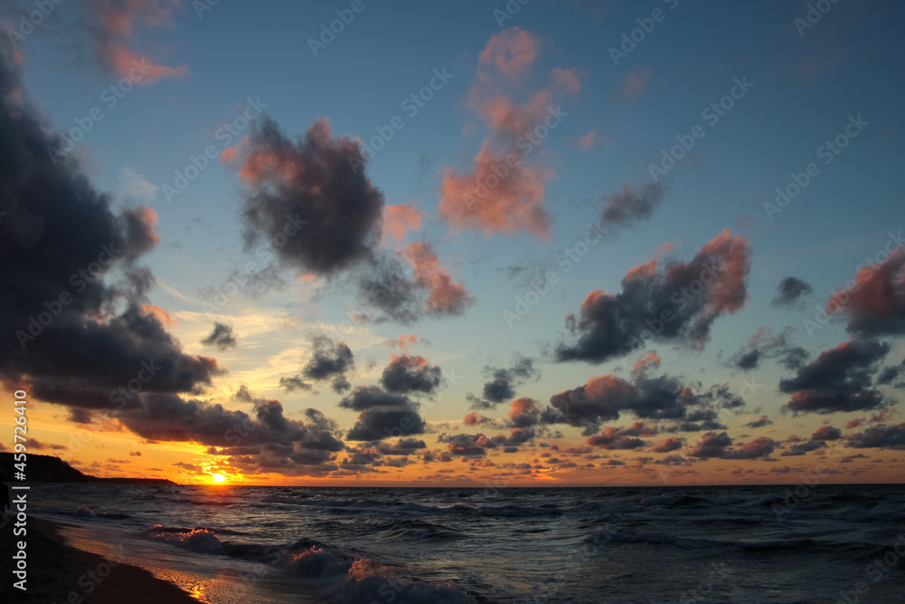 Beautiful sunset over the sea with red reflexes on clouds 