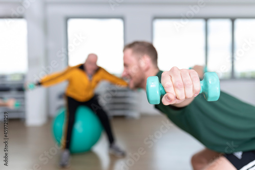 Junger Fitnesstrainer mit hanteln, Rehasport, Fitness