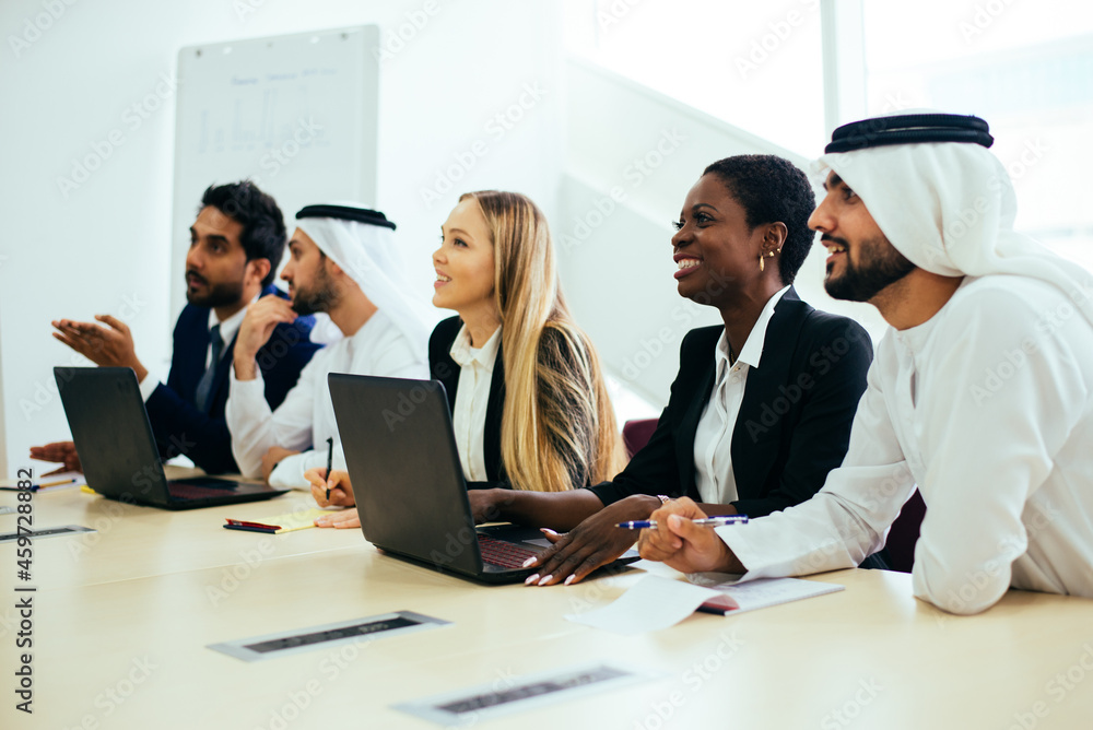 Mixed business team in Dubai. Business meeting with men wearing kandura and western people in the office Mixed business team in Dubai. Business meeting with men wearing kandura and western people in the office