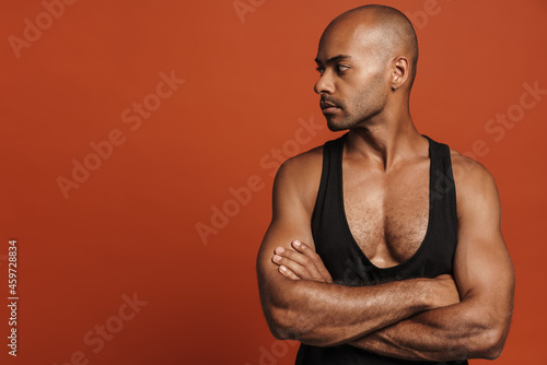 Black bold man wearing shirt posing with arms crossed