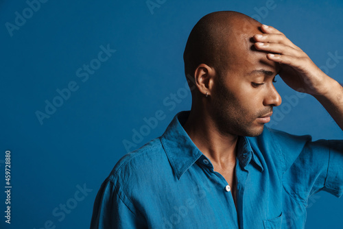 Black bold man with headache rubbing his forehead