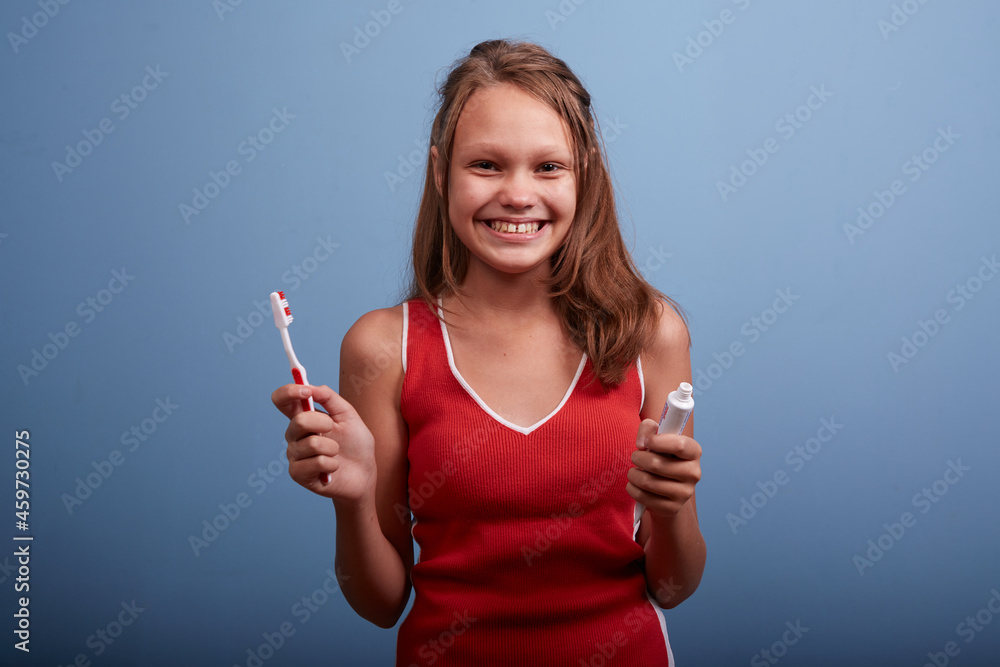 a beautiful girl of 11 years old brushes her teeth on a blue background a beautiful girl of 11 years old brushes her teeth on a blue background