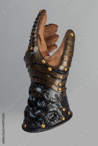 Medieval knightly brown plate gauntlet from Italian armor, in the form of a lion's face and mane, period of the 16th century, on a light background. photo