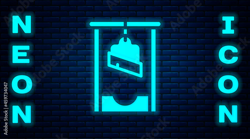 Glowing neon Guillotine medieval execution icon isolated on brick wall background. Vector