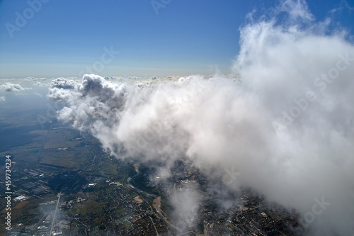 Aerial view from airplane window at high altitude of earth covered with white puffy cumulus clouds. © bilanol