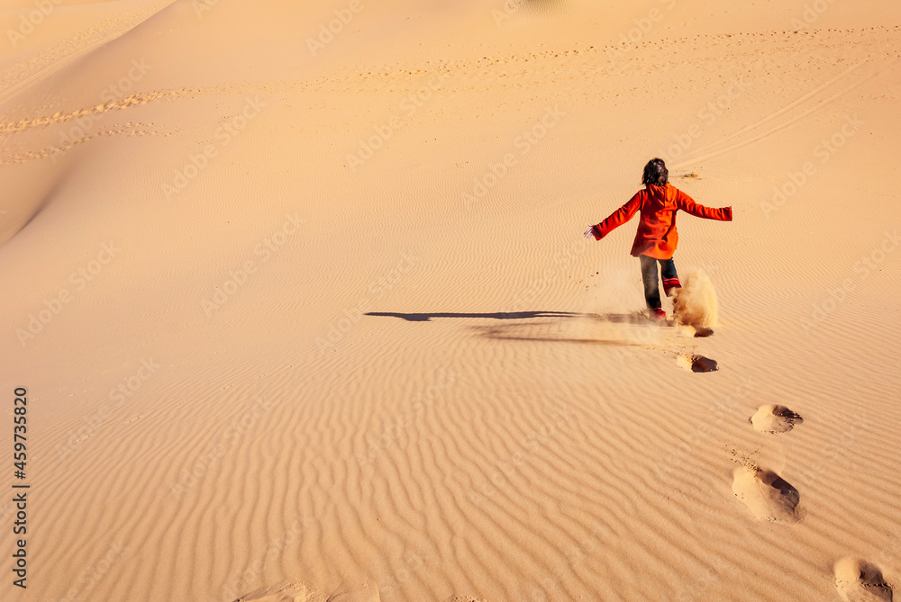 Fototapeta premium woman running happily down a desert dune