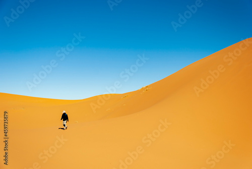 man walking in the desert dunes