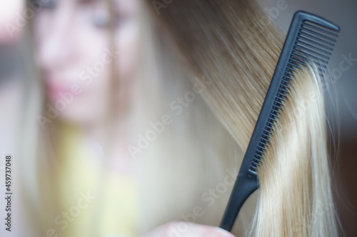 Young woman with a lock of shatush hair close up. The process of combining with a fine black comb. photo