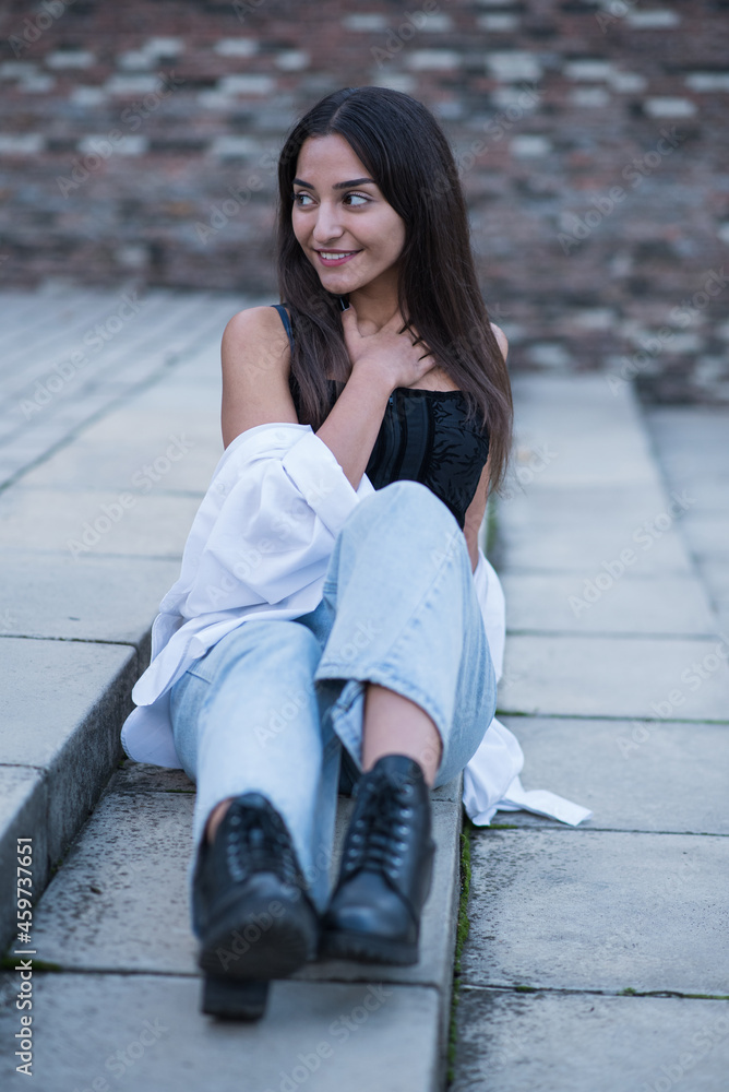 Young and attractive Caucasian or Arabian brunette girl posing while sitting on the steps. Young and attractive Caucasian or Arabian brunette girl posing while sitting on the steps.