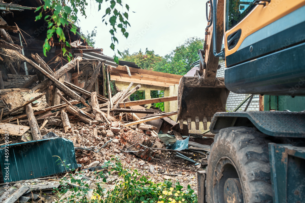 Fototapeta premium Demolition of house. Broken walls of old building and excavator at site of future construction.