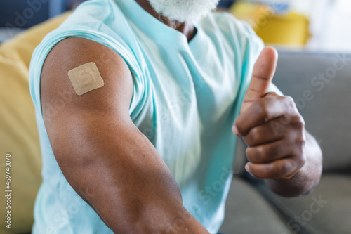 Close up of senior african american man in living room with bandage on his arm and thumb up