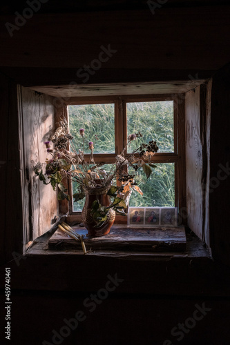 dried flowers in a pot on a window in a small wooden village chapel