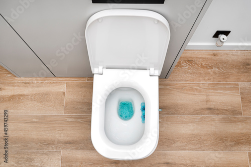 Foto A white ceramic toilet with an open flap in a modern bathroom, a floor covered with ceramic tiles imitating wood, top view