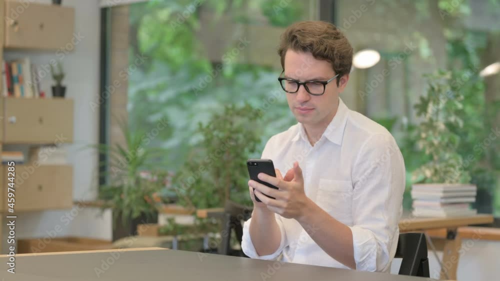 Attractive Young Man Using Smartphone in Modern Office Attractive Young Man Using Smartphone in Modern Office