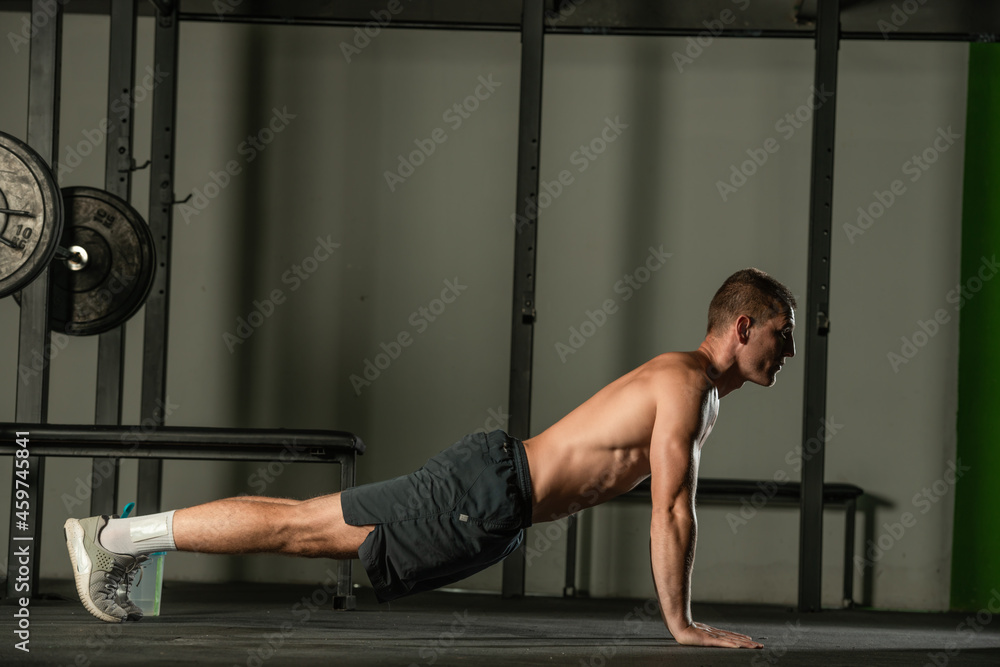 Fototapeta premium Strong male athlete doing push-ups indoors. Close up perspective, healthy lifestyle, fatless body.
