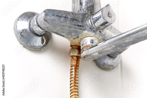 The faucet, mixer and hose in the bathroom are rusty, dirty, calcined with limescale. close-up. side view