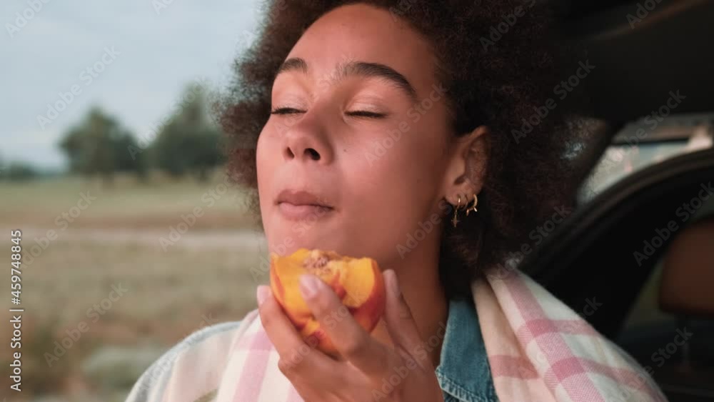 Close-up view of the handsome woman eating peaches in nature Close-up view of the handsome woman eating peaches in nature