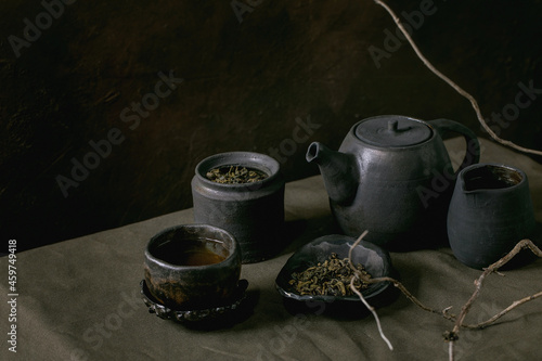 Set of craft handmade ceramic teapot and cups with dark background photo