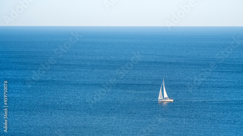 alone white sailboat rides in summer day at blue sea with horizon and copy space in frame ratio 16 to 9 © sergejson
