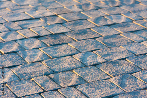 Medieval pavement made of square stones, illuminated by the morning sun