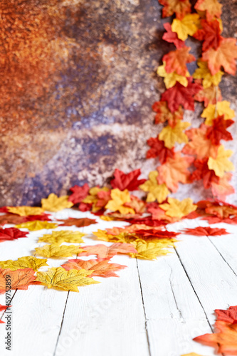 Autumn decoration with decorative colorful maple leaves on white wooden background. Autumn vibes. Thanksgiving decor. Space for text. Selective focus.