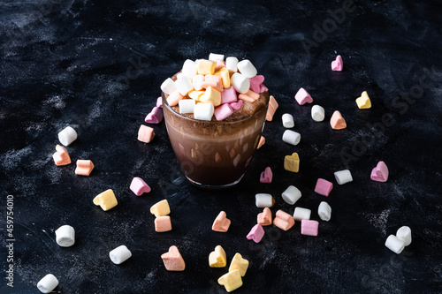 A cup of coffee with marshmallow on dark background