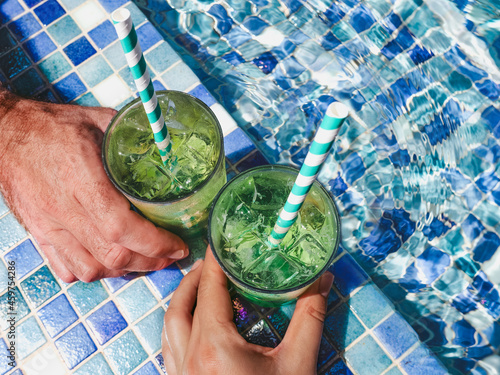 Two beautiful glasses with a refresh cocktail on the background of the pool. View from above, close-up. Vacation and travel concept. Moments of celebration