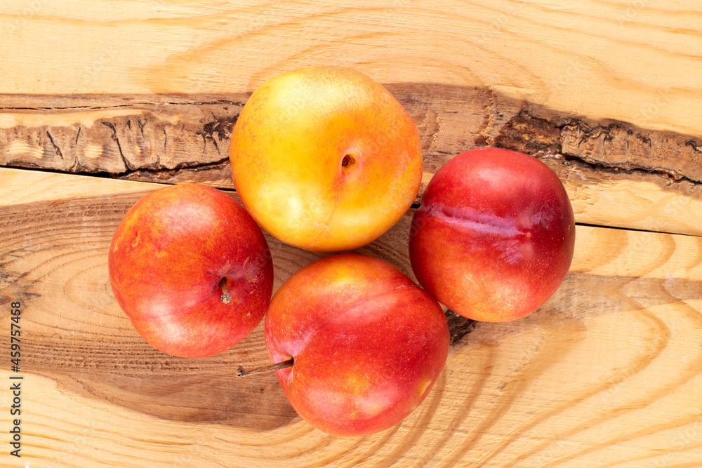 Several juicy sweet yellow-red plums on a wooden table, close-up, top view. Several juicy sweet yellow-red plums on a wooden table, close-up, top view.