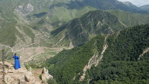woman in a blue long dress stands on top of the roof on an abandoned village
