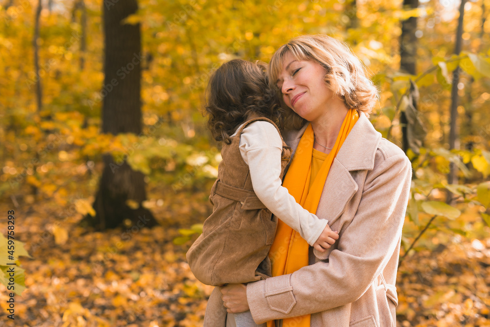Young mother with her little daughter in an autumn park. Fall season, parenting and children concept. Young mother with her little daughter in an autumn park. Fall season, parenting and children concept.