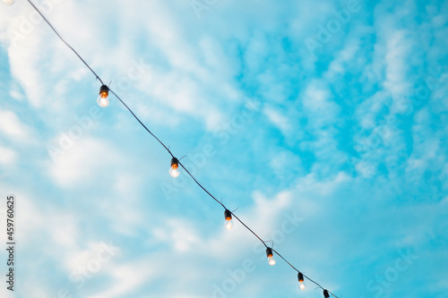 Fashion decoration string lights hanging in restaurant or cafe in the garden at summer party. Outdoor electric lamps