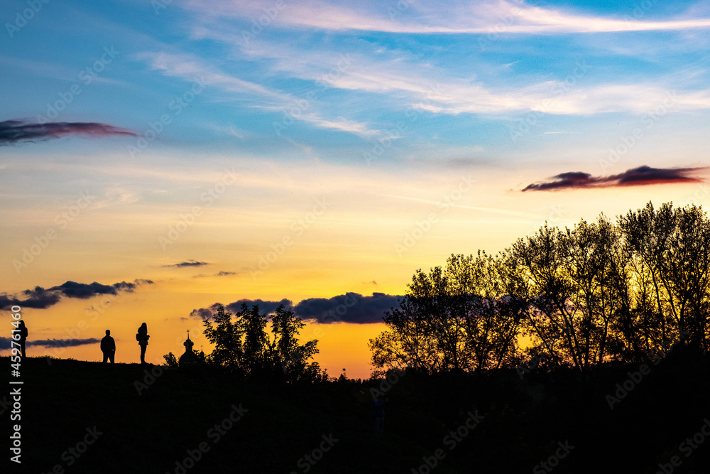 Silhouettes of people, trees and domes of churches on the beautiful sunset sky in Suzdal.