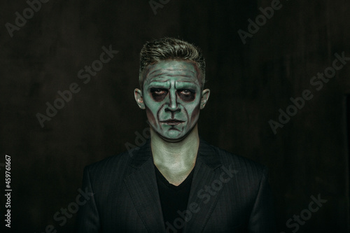 A man in the image of Frankenstein  green makeup  dark jacket  Halloween. The image of a man on Halloween