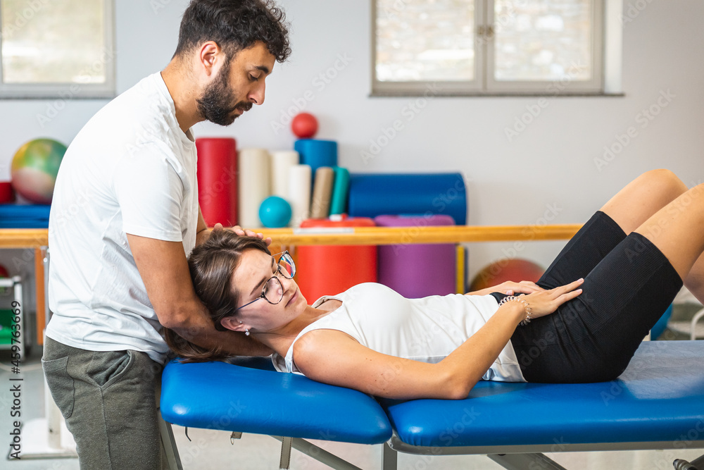 Physiotherapist doing manual stretching and resistance techniques to reduce neck pain in a young Caucasian female patient. Physiotherapist doing manual stretching and resistance techniques to reduce neck pain in a young Caucasian female patient.