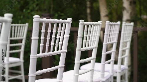 White plastic Chiavari chairs in rows. Outdoor wedding ceremony. photo