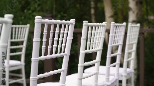 White plastic Chiavari chairs in rows. Outdoor wedding ceremony.