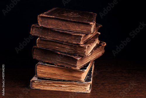 Stack of old worn shabby books in leather binding on dark background. Closeup. Selective focus.